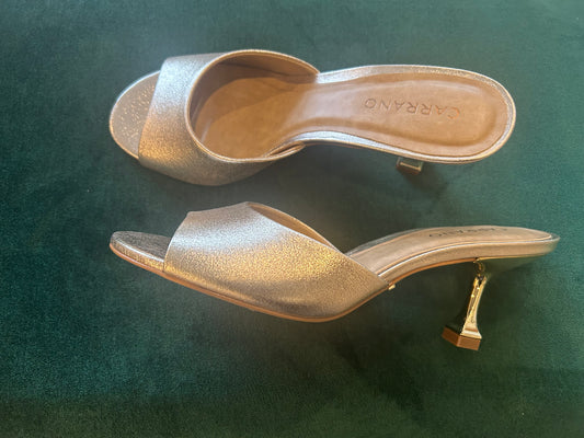 Gold heel slide sandals with an elegant design, featuring a shiny metallic finish and a comfortable slip-on style, perfect for formal or casual occasions."