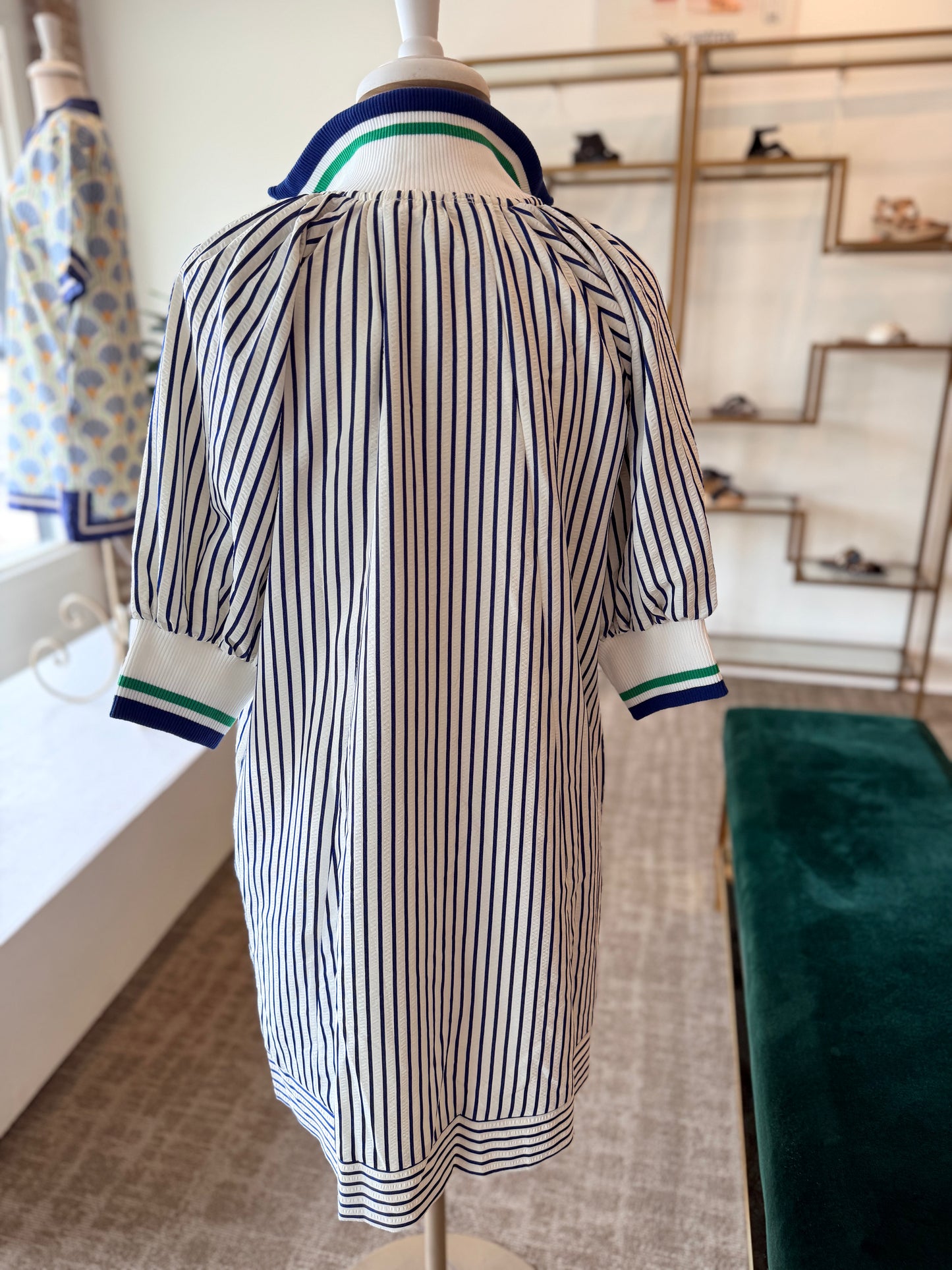 Mannequin wearing a striped dress with green accents in a store setting