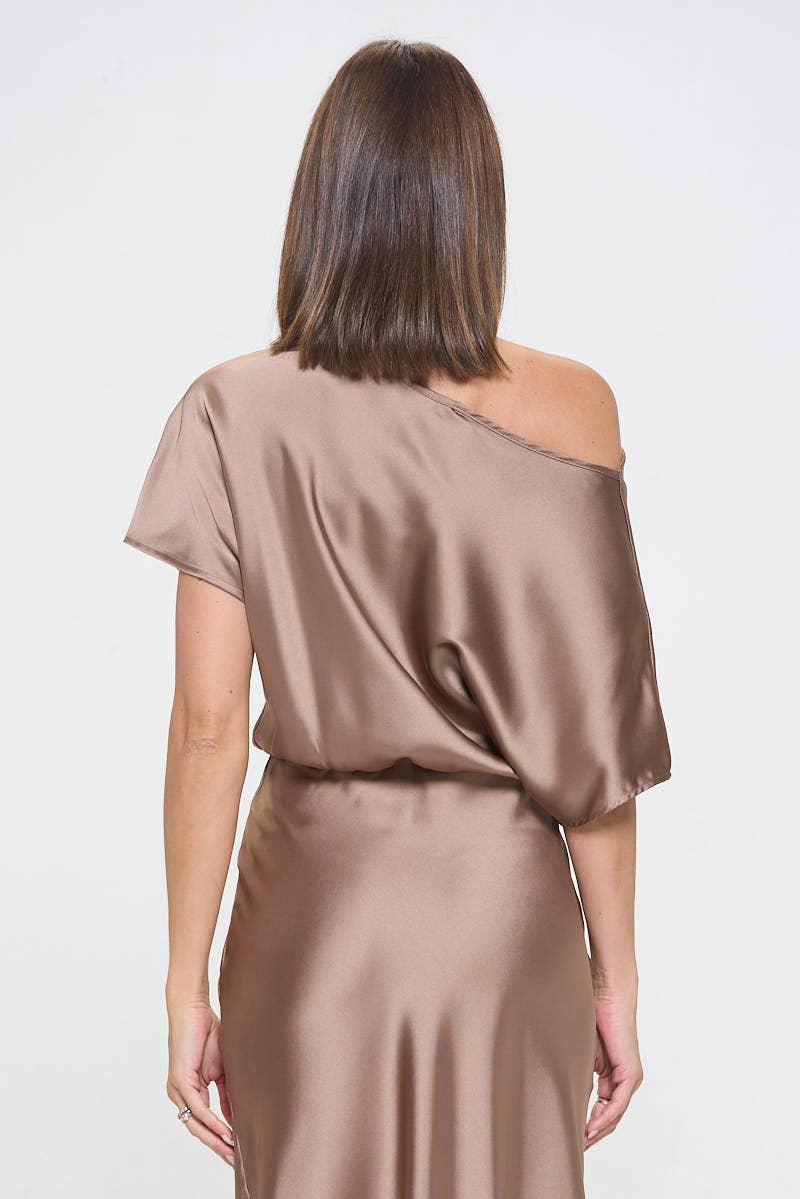 Woman wearing a beige satin off-shoulder dress on a white background